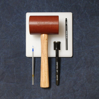A bakelite mallet, poly punching board, drive punch, and leather marking pen laid out for making leather straps