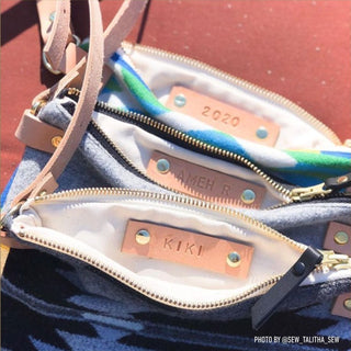 Three zipper pouches in blue Pendleton wool, unzipped to show leather labels riveted inside, hand-stamped 2020, AMEH R and KIKI