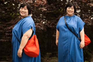 Two views of a maker in a blue dress wearing a persimmon Naito Bucket Bag on a long dark leather crossbody strap, standing in front of a Japanese maple.